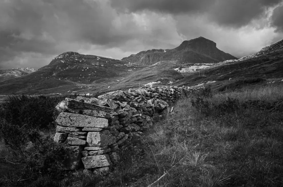 Steingjerde i fjellet under skyer